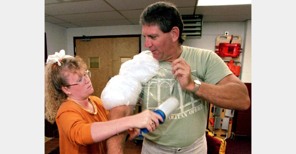 Athletic trainer Dawn Ward wraps ice onto the shoulder of Chuck Roseberry, a 46-year-old defensive tackle at Kutztown University after football practice on Sept. 1, 1994